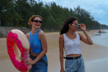 Friends enjoy sunny day at beach, laughing and relaxing by sea during summer. Their carefree spirit captures essence of friendship and fun in sun