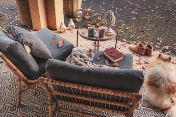 Cozy autumn (fall) home terrace with two soft chairs, hot tea, coffee and a book. Relaxing outdoor nook.