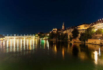 A night, long exposure, panorama of the Rhine in Basel with the brightly lit bridge and cathedral in the background.