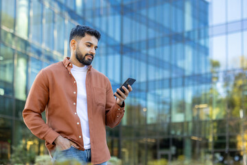 Man using smartphone outside modern urban office building during daytime