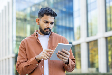 Professional man using a tablet in a modern urban outdoor setting