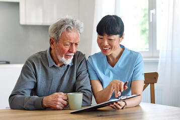 Female caregiver with senior woman and man using laptop at home
