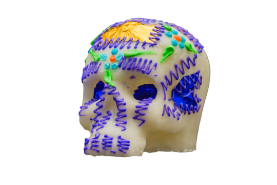 Colorful sugar skull decorated with purple icing and foil accents isolated