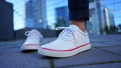 Close up of white platform sneakers with red trim on a city street