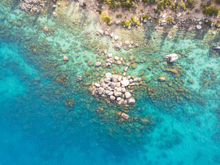 Aerial view of the turquoise lake swirling around  smooth, grey rocks,  Lake Tahoe, USA