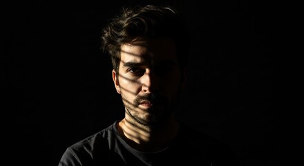 Naklejka premium Mans face shadowed by light dark hair and beard visible