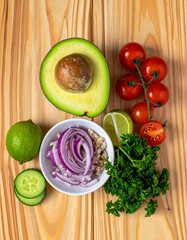 Top View Still Life of Fresh Avocado, Quinoa, Cherry Tomatoes, Red Onion, Cucumber, Lime, and Parsley – Healthy Salad Ingredient Composition on Natural Wood Background