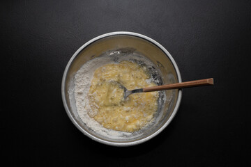 A pile of flour and a broken egg in a bowl. View from above. Making dough from delicious wheat flour. The process of cooking.