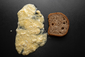 A pile of dough flour and a piece of fresh bread on a black background. Top view. Making dough from delicious wheat flour. The process of cooking.
