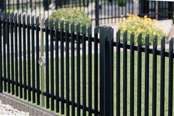 Black metal fence detail with vertical bars, modern garden security barrier and protective boundary in outdoor residential property landscape