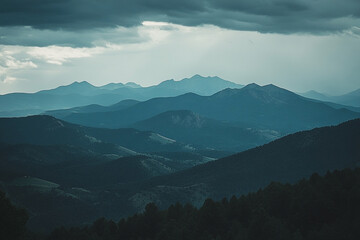 Serene Layers: Majestic Mountain Range Shrouded in Mystical Blue Hues Beneath Overcast Sky