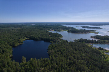 The Baltic coast in the Gulf of Bothnia in southern Finland - a lake, islands, a rocky shore, forests, bays and a cloudless sky - a photo from a drone