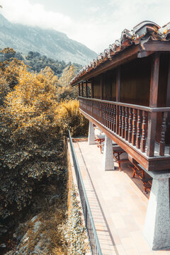 Elevated traditional wooden horreo in Asturias transformed into a rustic home with tiled terrace, surrounded by golden autumn trees and misty mountain scenery in northern Spain