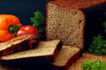 Rustic still life with bread salami vegetables and herbs on dark background