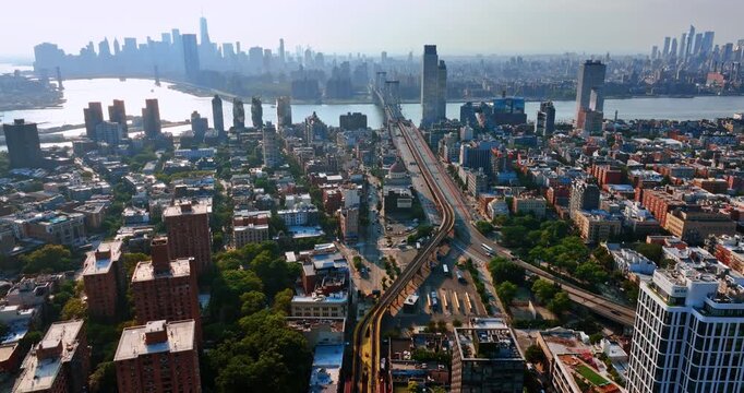 Roads and railways leading to the Williamsburg Bridge over the East River. Sunlit panorama of New York at backdrop.