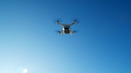 Modern white drone taking off and flying high into the bright blue sky on a sunny day. - Powered by Adobe