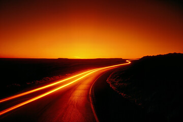 Naklejka premium Curved highway at sunset with headlight motion blur on road