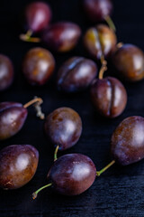 Ripe plums on black table.