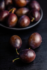 Ripe plums on black table.