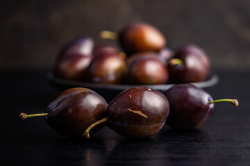 Ripe plums on black table.