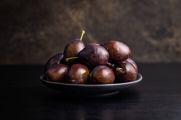 Ripe plums on black table.