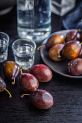 Plums and distilled alcohol on black table. Plum brandy shot.