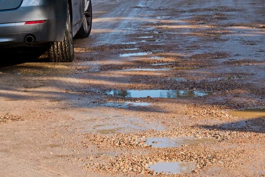 Car on muddy rural road with puddles after rain