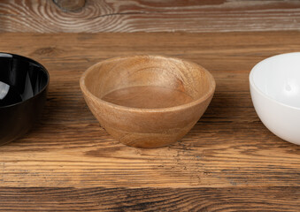 Three empty bowls on table, white porcelain, black and wooden dishes on tabletop, rustic dish