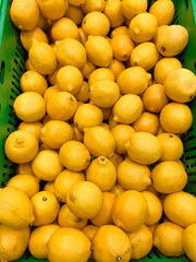 Vibrant yellow lemons piled high in a green basket at a bustling market