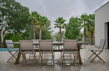 TABLE AND CHAIRS ON THE TERRACE UNDER THE RAIN