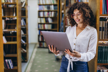 Young student researching using laptop in library