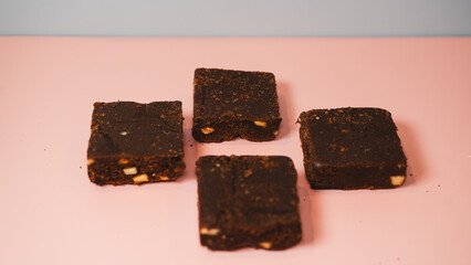 Decadent, fudgy chocolate brownies presented on a vibrant pink and blue background. Ideal for bakery advertising, dessert blogs, or social media content. Professional food photography with bold colors