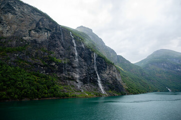 Mountain landscape with cloudy sky. Beautiful nature Norway. Geiranger fjord. Seven Sisters Waterfall