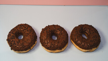 Three rich chocolate donuts with glossy glaze, captured in a close-up to showcase their decadent texture and appeal. Ideal for dessert menus, bakery promotions, and social media content.