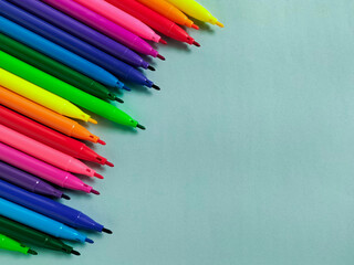 Colorful markers are arranged against light green background.