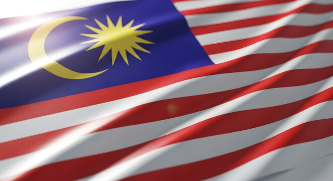 The Malaysian flag, Jalur Gemilang, waving gracefully in the wind with a bright lens flare.
