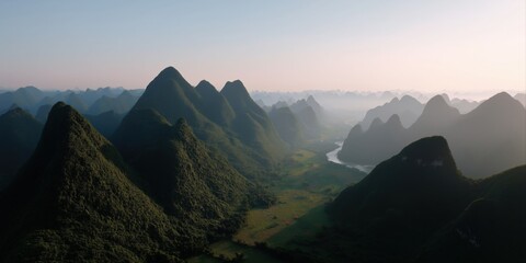 Misty mountain range and serene river at sunrise in lush green valley