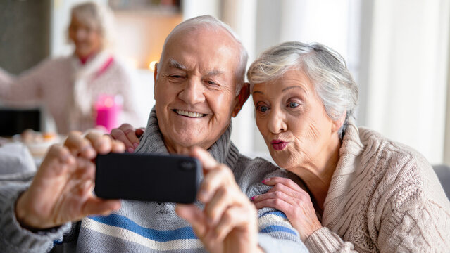 Happy senior couple taking selfie with smartphone, elderly using technology at home, digital lifestyle and joyful aging moments