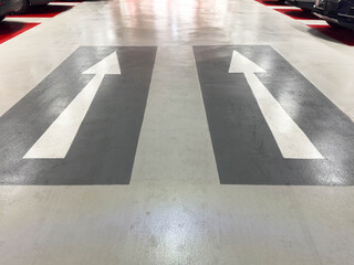 Directional arrows on parking garage floor indicating one-way traffic flow