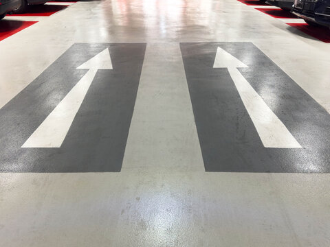 Directional arrows on parking garage floor indicating one-way traffic flow