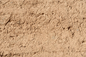 Original unedited close-up photo of traditional clay and straw adobe (Kahgel) wall in Yazd, Iran, showcasing textured earthy surface and desert architecture.