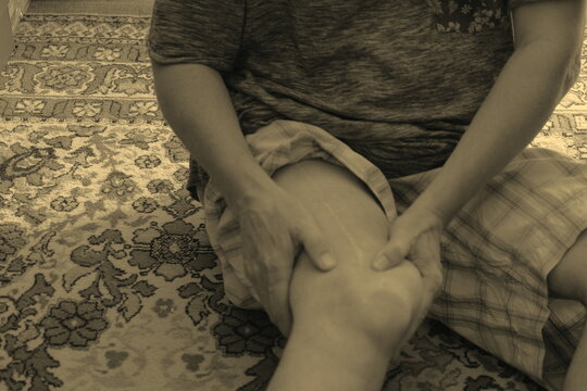 Man doing sports while kneading a man's sore leg and hands and feet on the floor