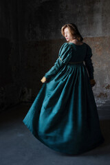 Enchanting lady in rich green period costume, golden tresses framing her face near ancient walls