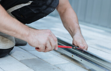 An unrecognizable handyman tightens a bolt with a screwdriver.