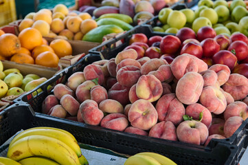 Colorful selection of fresh fruits, including peaches, bananas, and apples, on display at a farmers market. Vibrant and healthy produce ideal for vegetarians, vegans, and healthy lifestyle choices.