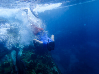 Obraz premium Young man diving underwater and taking pictures with his phone, Man undersea wearing swimming fins and goggles enjoying marine life, Man scuba diver using smartphone underwater housing when shooting