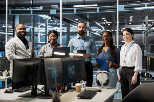 Portrait of smiling engineering team working in server farm, analyzing data. Happy teamworking employees examining infrastructure in data center, ensuring system integrity and security - Powered by Adobe