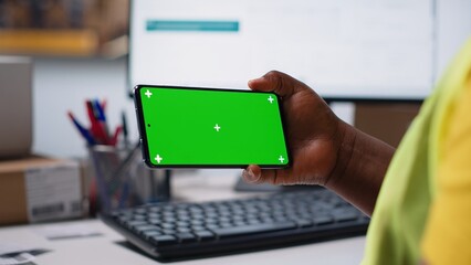Storehouse worker in hi vis vest uses chroma key display on phone for shipping software management, packaging systems and inventory management tools. E-commerce logistics. Camera B.