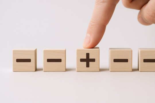 Adding Value: Finger Selecting Plus Sign Block Among Minus Symbols Representing Growth and Improvement