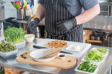 The chef prepares a flatbread with herbs. 